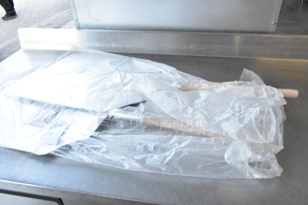 Brand new scratch and dent metal pizza peel wrapped in plastic. Two items included in auction.