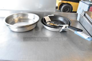 Four brand new kitchen items: two 407IND6FP Acopa Voyage 6 Qt chafers, Vollrath Tribute fry pan, Vigor A3000 14" aluminum fry pan with non-stick coating and silicone grip.