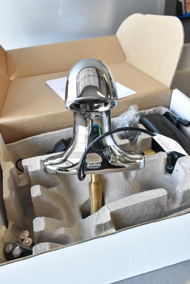 Brand new Zurn ZG6955 faucet in packaging, scratch and dent condition, chrome finish, visible Zurn logo, parts included.