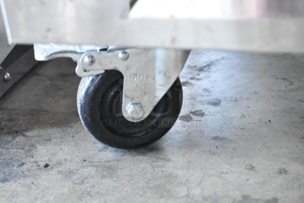 Close-up of a commercial caster on the Grand GT-54R-HC cooler, showing its sturdy construction and mobility feature.