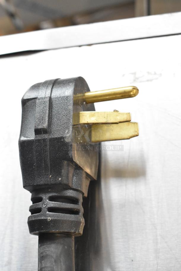 Close-up of Perfect Fry Company PFC570 fryer power plug. Black plastic with brass prongs, 208 Volts, 1 Phase.