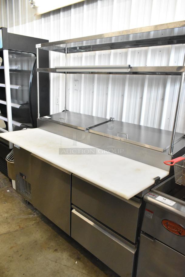 Avantco 178SSPPT2 stainless steel pizza prep table with oversized cutting board, 2-tier shelf, 2 drawers, and door on casters.
