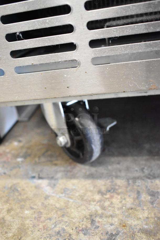 Close-up of a caster wheel on the 2024 Avantco 178SSPPT2 stainless steel pizza prep table.
