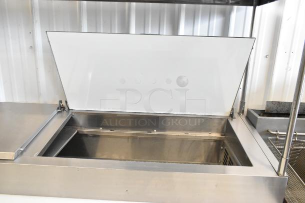 Avantco 178SSPPT2 stainless steel pizza prep table with oversized cutting board, 2-tier over shelf, drawers, door, and casters.
