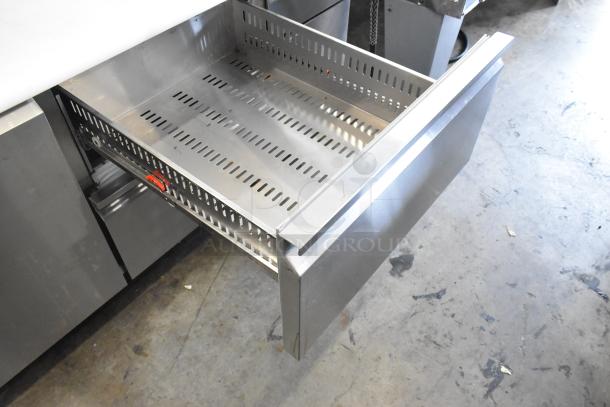 2024 Avantco 178SSPPT2 stainless steel pizza prep table with open drawer, oversized cutting board, and commercial casters.