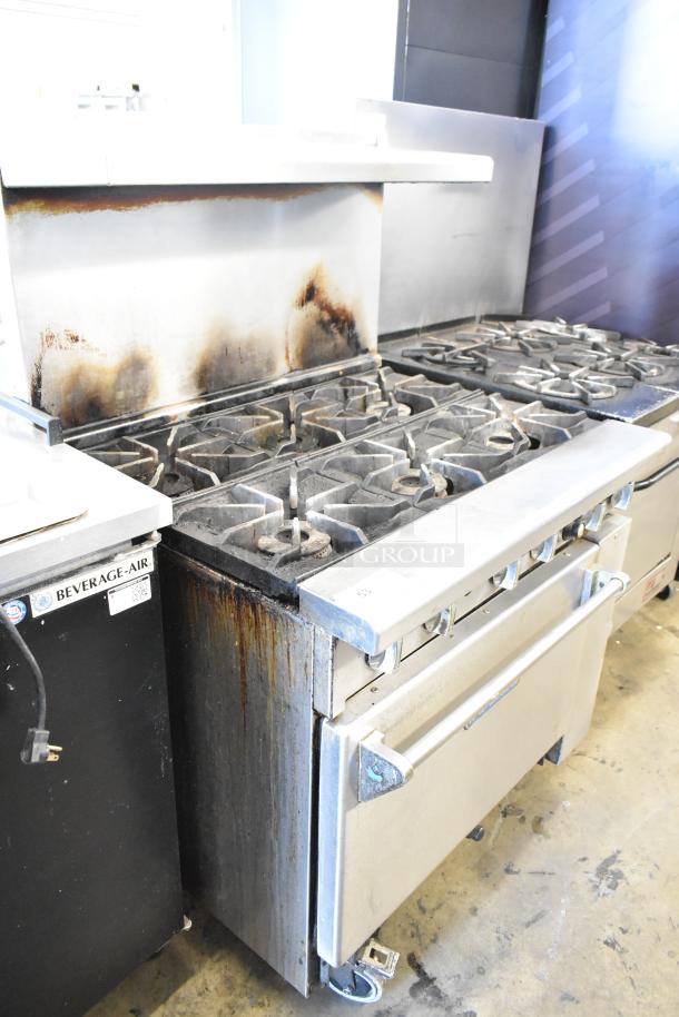 Imperial stainless steel commercial 6 burner gas range with oven, overhead shelf, backsplash, on casters. Visible wear on surfaces.
