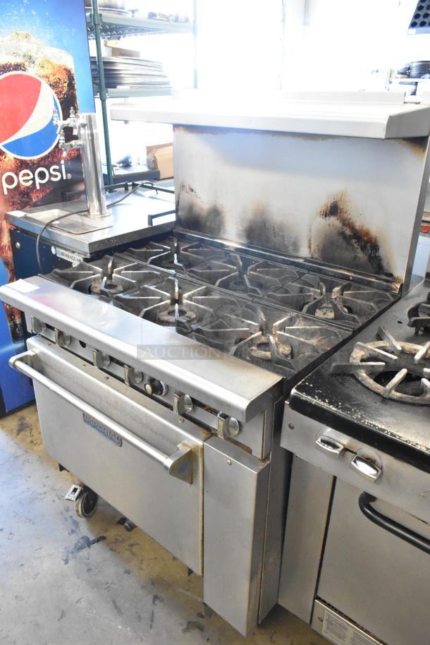 Imperial Stainless Steel 6-burner gas range with oven, over shelf, backsplash, commercial casters; visible wear and use.