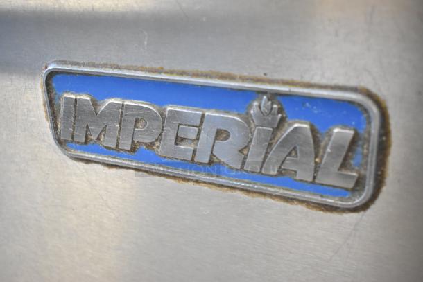Imperial logo on stainless steel commercial gas range. Features 6 burners, oven, over shelf, backsplash, and casters.