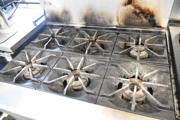 Imperial 6-burner commercial gas range, stainless steel, with oven, over shelf, backsplash, and casters, in used condition.