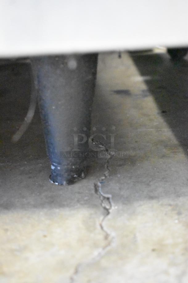 A detailed close-up of damaged flooring beneath the Southbend stainless steel gas range's leg. Condition issues visible.