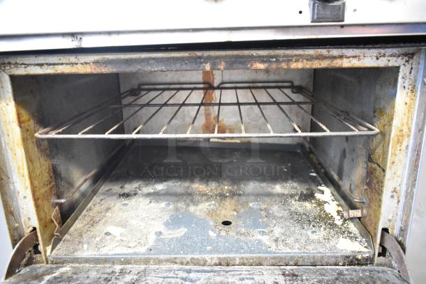 Southbend stainless steel commercial gas range; 6 burners, oven, backsplash, used condition, visible wear inside oven.