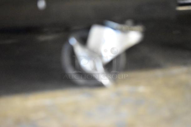 Blurry image of a commercial caster wheel on a hard surface, part of the Akita AGF-43-NY cooler.