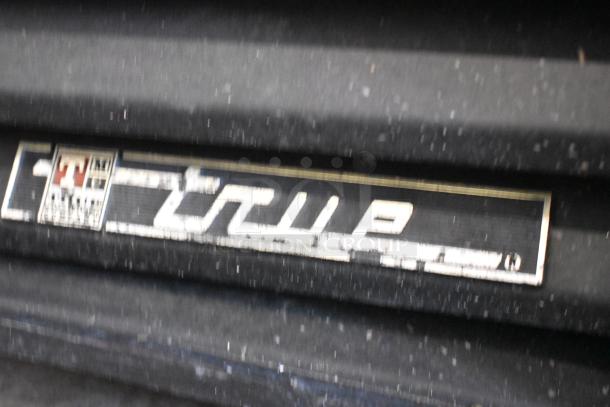 True GEM-26 cooler label, blurry text shows "True" branding. Black surface with dust, indicating used condition.