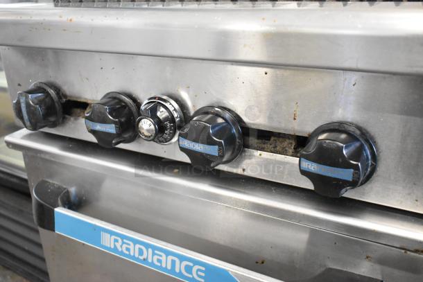 Radiance stainless steel gas charbroiler grill with oven, featuring control knobs, back splash, and commercial casters.