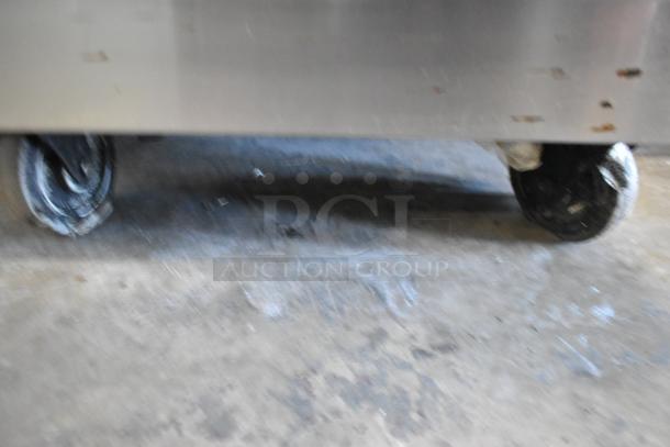 Radiance stainless steel commercial gas charbroiler grill with oven and back splash, on commercial casters.