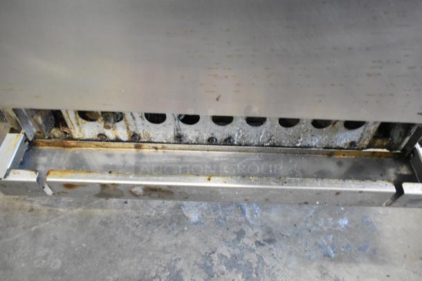 Radiance stainless steel commercial gas charbroiler grill with oven, featuring a back splash and casters. Used condition.