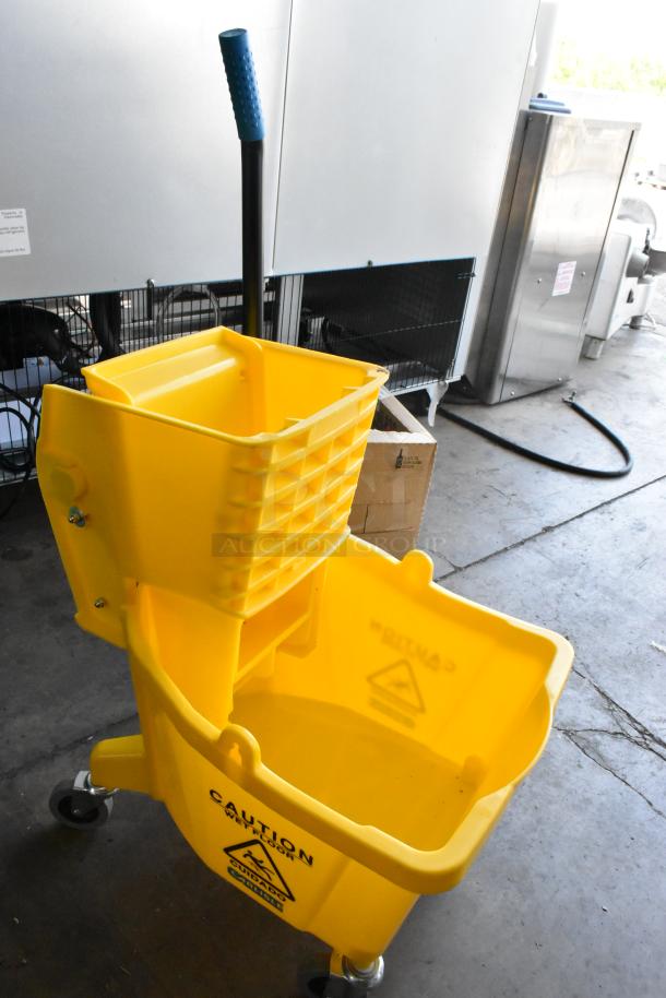 Yellow poly mop bucket with wringing attachment, on casters. "Caution Wet Floor" label visible. Excellent condition.