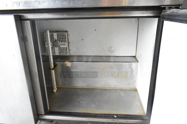 True TWT-60F stainless steel commercial 2-door work top freezer interior showing shelves and cooling unit, on commercial casters.