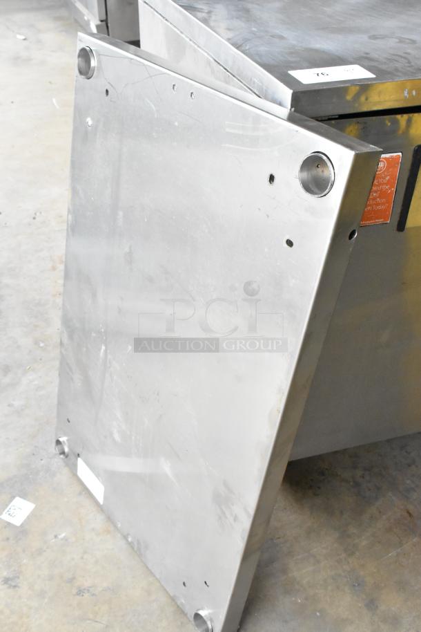 Stainless steel panel with pre-drilled holes, brushed finish, minor surface scratches, and slightly bent edges. Auction tag visible.