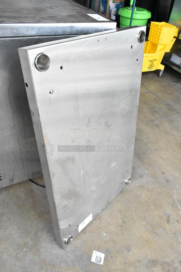 Stainless steel panel with visible surface marks and mounting holes, used condition. Label with numeric code attached.