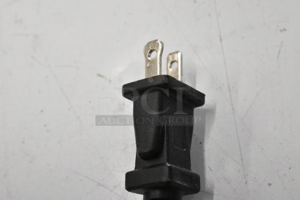 Close-up of a black power plug with two metal prongs, part of tool auction including Hilti and DeWalt items.
