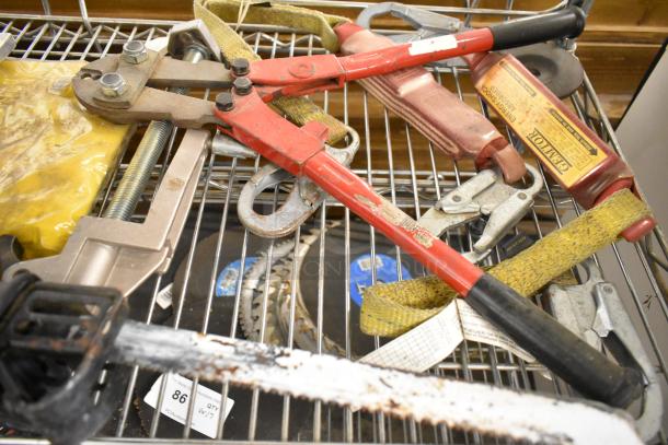 Assorted tools including red bolt cutter, yellow strap, and hand saw on metal shelf; visible markings on red tool handle.