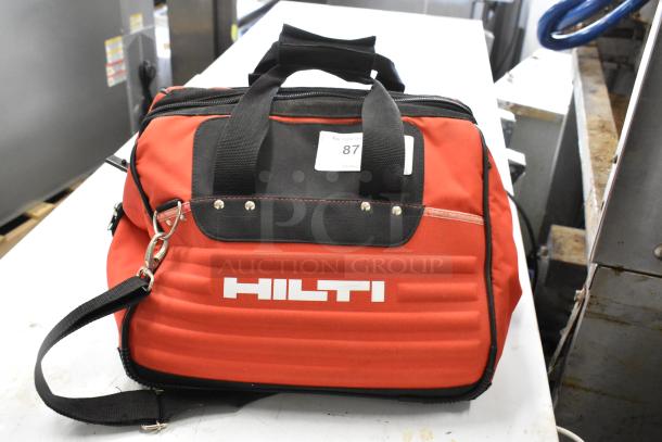 Red Hilti tool bag with logo, includes clamps. Sturdy design, black straps. Excellent condition, auction item label visible.