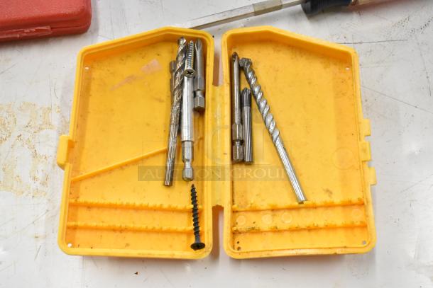 Yellow case containing various metal drill bits and a screw, visible tool marks and wear.