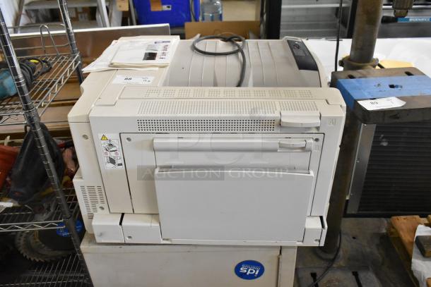 Two Xerox Phaser 7500 printers, off-white, with visible condition wear. Includes printed labels on top. Auction item.