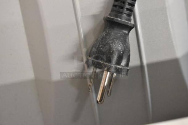 Close-up of a black power plug for a Xerox Phaser 7500 printer against a gray background.