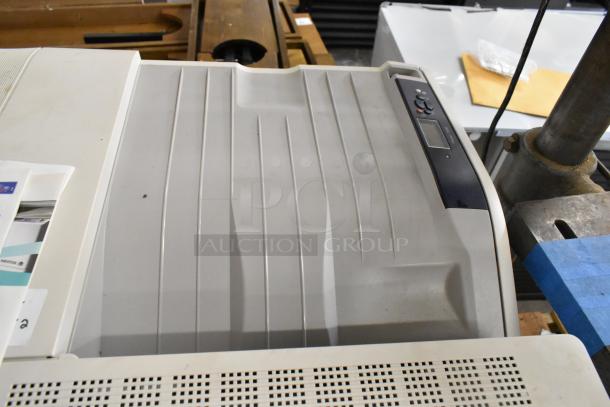 Two Xerox Phaser 7500 printers, light gray, with control panel, visible paper tray, and some surface wear.