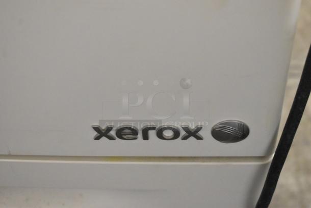 Xerox Phaser 7500 printer close-up, featuring the Xerox logo. Condition appears used, visible wear on surface.