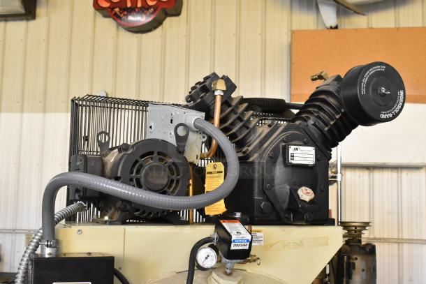 Ingersoll Rand 2475N5-V metal commercial air compressor, features durable construction, visible labels, industrial setting.