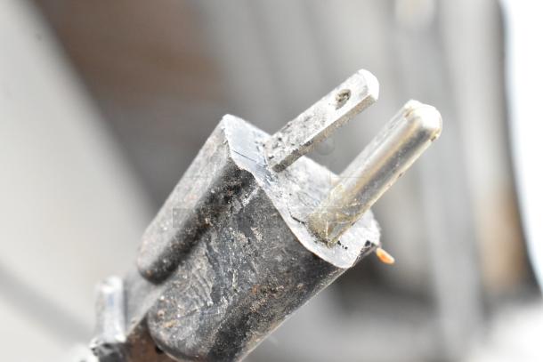 Close-up of a worn electrical plug, part of a Crathco D25-3 beverage machine, highlighting the power connection.