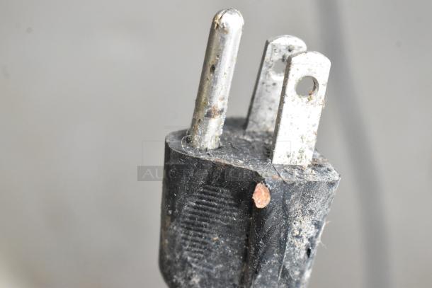 Close-up image of a plug, possibly from a Crathco D25-3 beverage machine, showing metal prongs and some dirt.