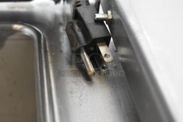 Close-up of a plug and metal surface, showing part of a Delfield 18699PTT Pizza Prep Table, stainless steel.