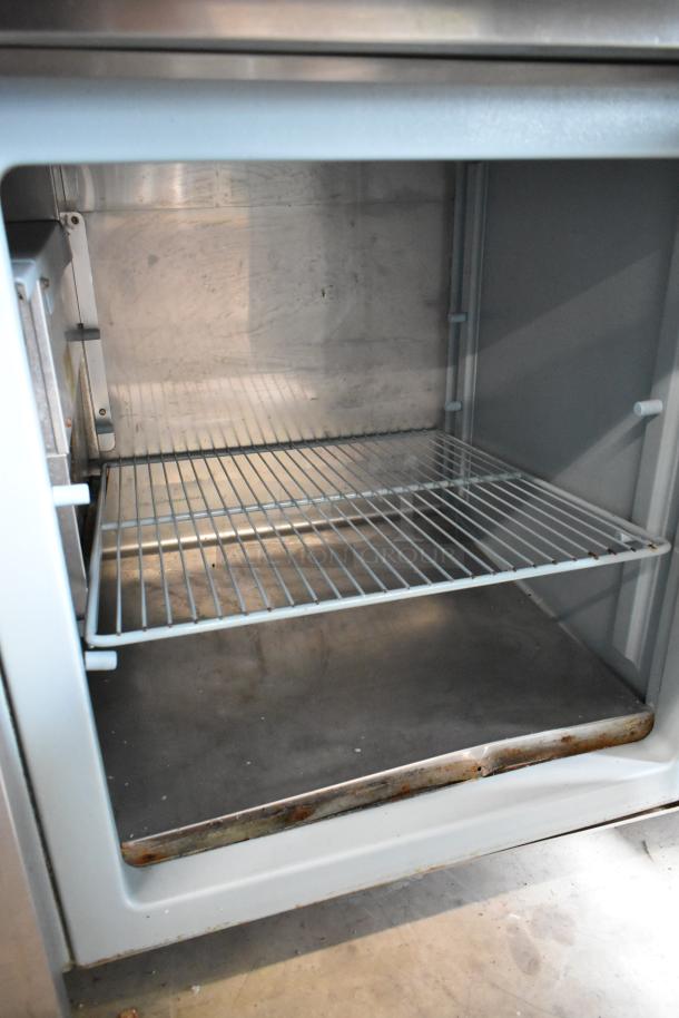 Delfield 18699PTT stainless steel pizza prep table with cutting board, features interior storage and wire shelving on casters.