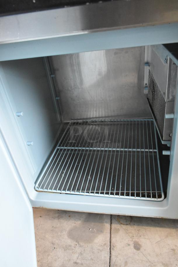 Delfield 18699PTT stainless steel pizza prep table with cutting board, shown open with interior shelving, on commercial casters.