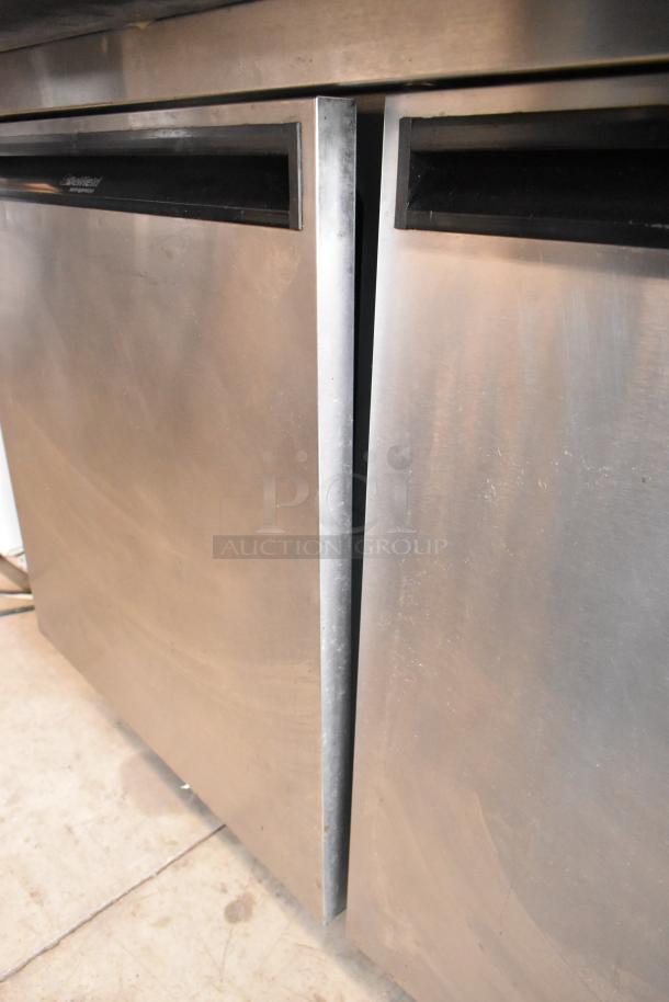 Delfield 18699PTT stainless steel pizza prep table with cutting board, commercial casters, 115V, 1-phase, visible wear.