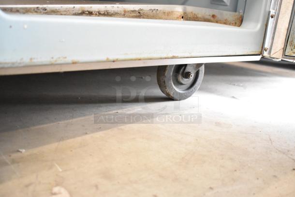 Delfield 18699PTT pizza prep table on a commercial caster, showing slight wear.