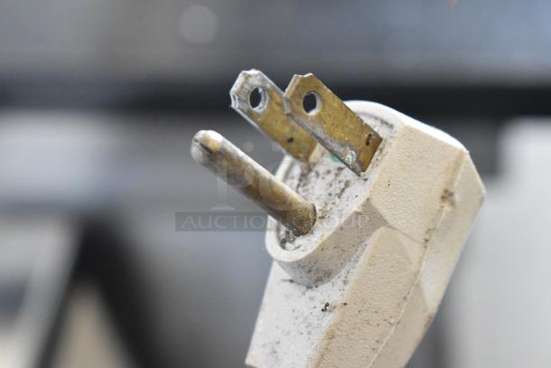 Close-up of an electrical plug for a Maytag MQU2057AEW freezer, 115 volts, showing signs of use.