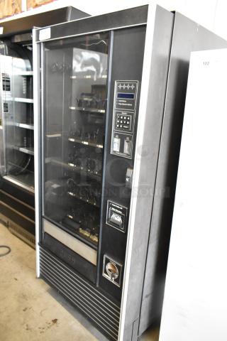 Metal commercial vending machine with key, featuring a coin slot, selection keypad, and glass display, in good condition.