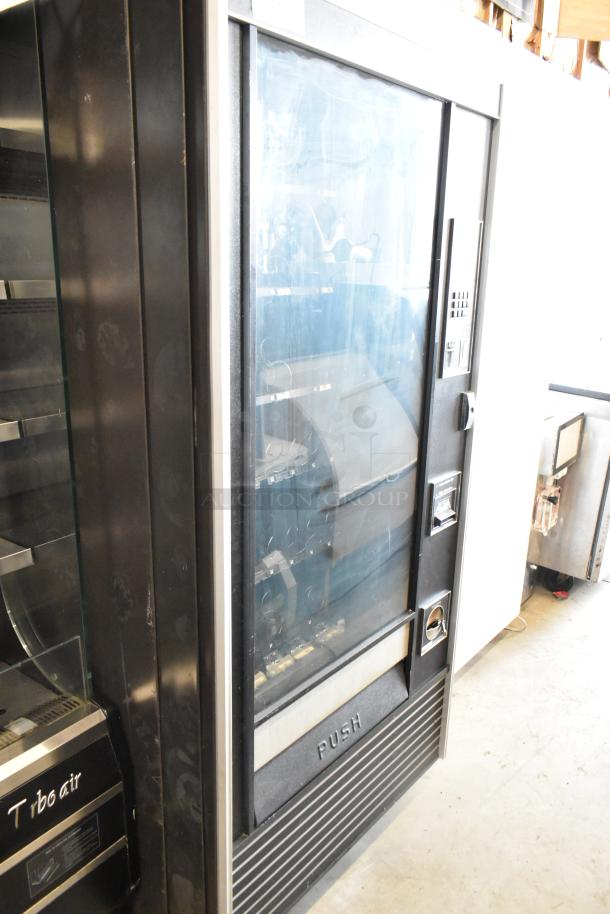 Metal commercial vending machine with a transparent front, coin slot, and keypad; includes a key. Good condition.