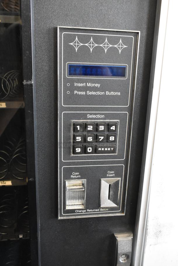 Metal commercial vending machine with keypad, coin insert, and key. Black casing, visible selection buttons, used condition.