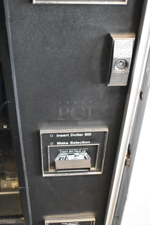 Metal commercial vending machine with lock and key, featuring a bill acceptor and coin return, in good condition.
