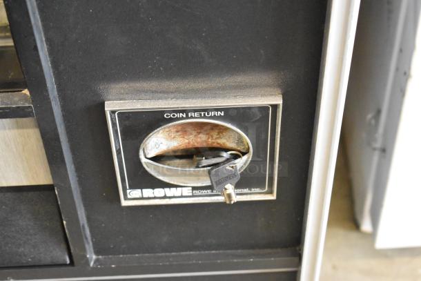Metal commercial vending machine with key, coin return feature, and Rowe International branding. Good condition.