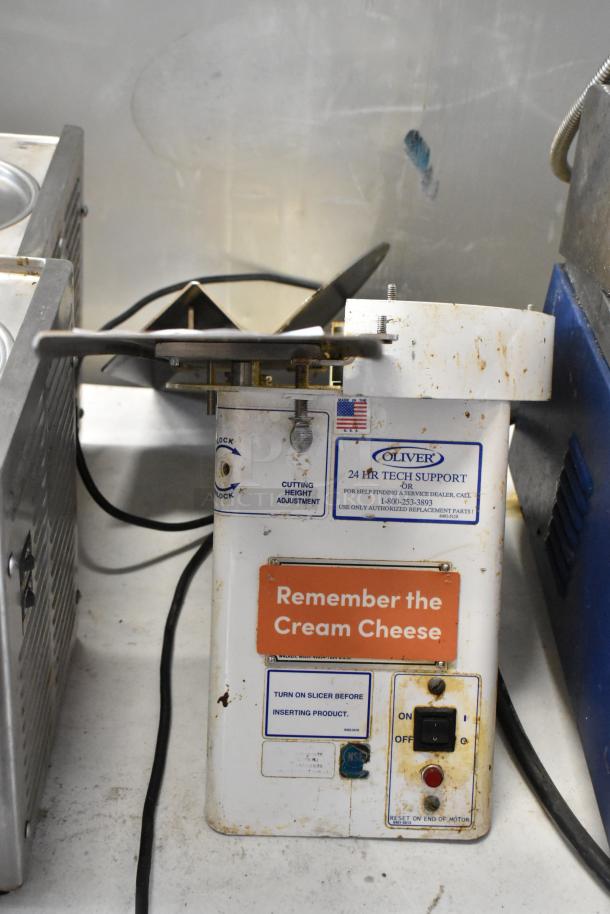 Oliver 702-N metal commercial countertop bagel slicer, 115 volts, 1 phase. Visible wear and markings for tech support and usage instructions.