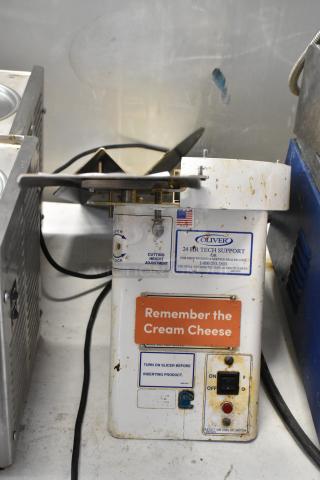 Oliver 702-N metal commercial countertop bagel slicer, 115 volts, 1 phase. Visible wear and markings for tech support and usage instructions.