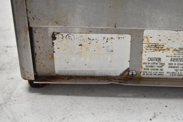 Crathco stainless steel 2 hopper beverage machine base, 115V, shows wear and rust, includes caution labels for electric safety.