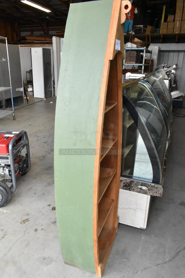 Wooden canoe-shaped shelving unit, green exterior, multiple shelves, good condition. Lot tag visible.